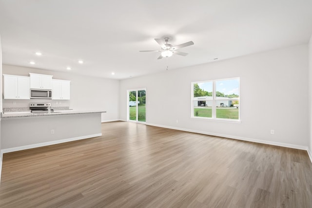 unfurnished living room with light wood-style floors, baseboards, a ceiling fan, and recessed lighting