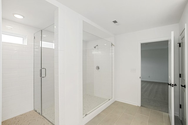 bathroom with a stall shower, tile patterned flooring, visible vents, and baseboards