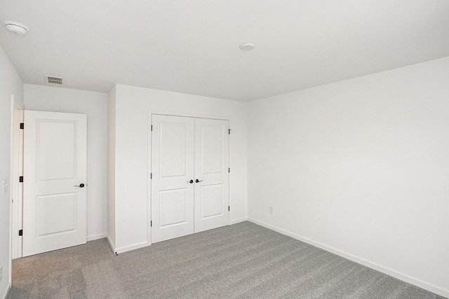 unfurnished bedroom featuring baseboards, a closet, visible vents, and carpet flooring