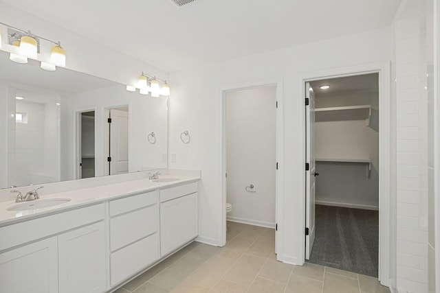 bathroom with a sink, a spacious closet, toilet, and double vanity