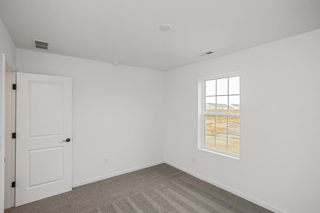 spare room featuring carpet flooring, visible vents, and baseboards