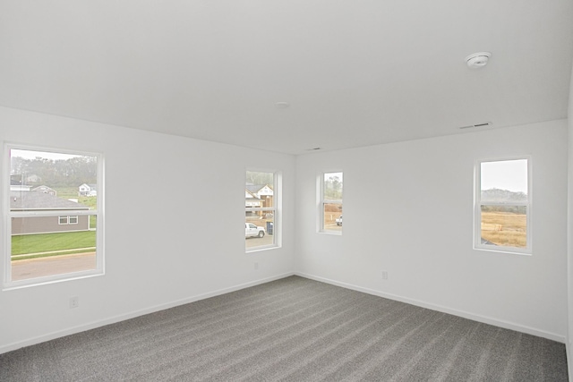 empty room featuring a healthy amount of sunlight, carpet, visible vents, and baseboards