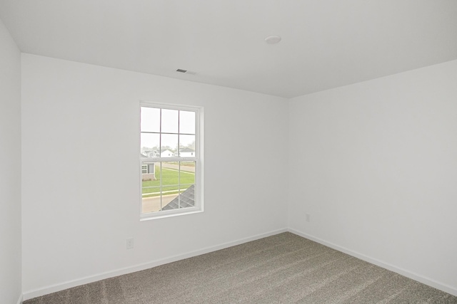 spare room featuring carpet floors, visible vents, and baseboards