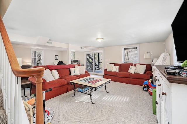 living room featuring carpet floors, visible vents, and stairway