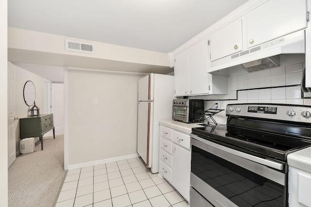 kitchen featuring visible vents, white cabinets, freestanding refrigerator, stainless steel range with electric cooktop, and under cabinet range hood