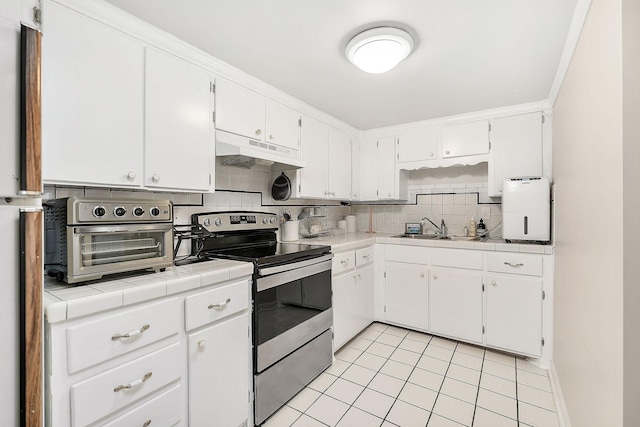 kitchen featuring tile countertops, stainless steel range with electric cooktop, white cabinetry, and under cabinet range hood