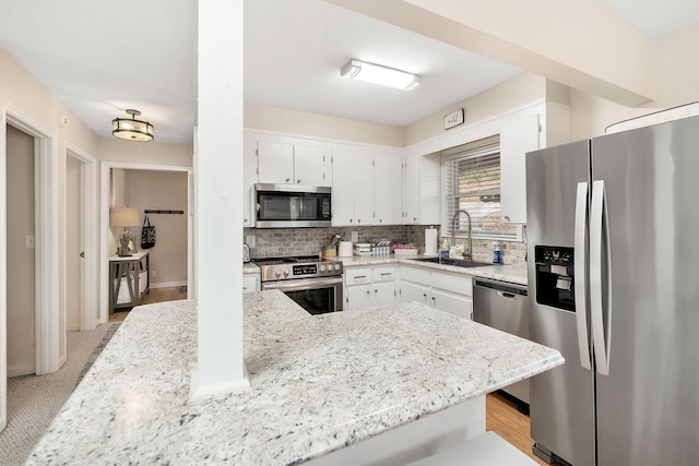 kitchen with stainless steel appliances, white cabinetry, a sink, and decorative backsplash