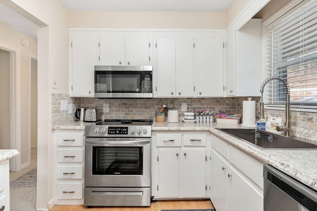 kitchen featuring white cabinets, stainless steel appliances, and a sink