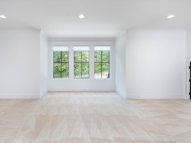 empty room featuring light carpet, recessed lighting, baseboards, and crown molding