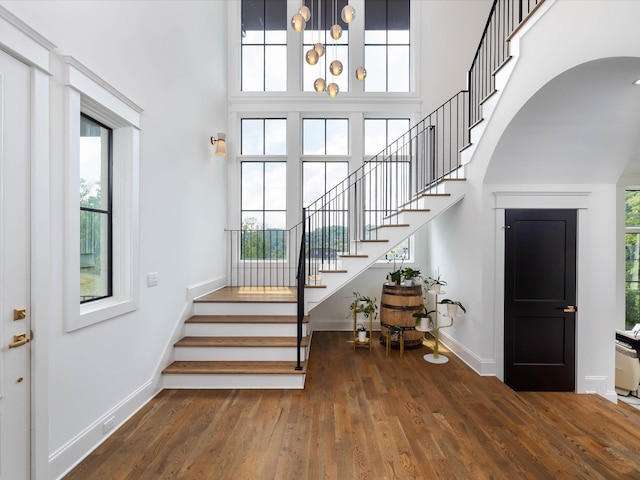 staircase with a high ceiling, wood finished floors, and baseboards