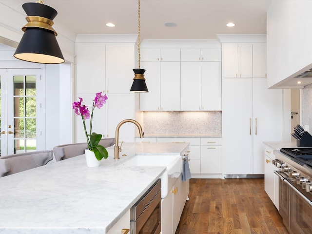 kitchen featuring dark wood-style flooring, white cabinets, decorative backsplash, and light stone countertops