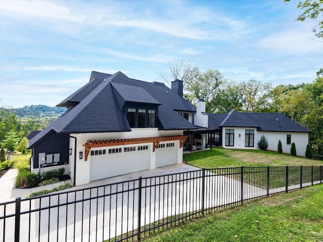 view of front of house with a fenced front yard, a chimney, a front yard, a garage, and driveway