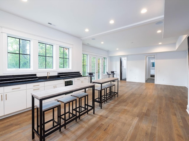 kitchen featuring visible vents, dark countertops, a breakfast bar, light wood-type flooring, and white cabinetry