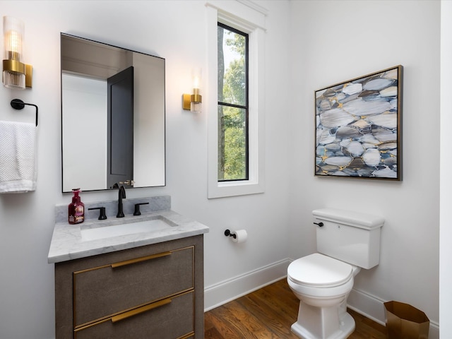 bathroom with toilet, baseboards, wood finished floors, and vanity