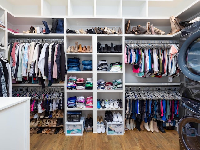 spacious closet featuring wood finished floors and stacked washer / drying machine