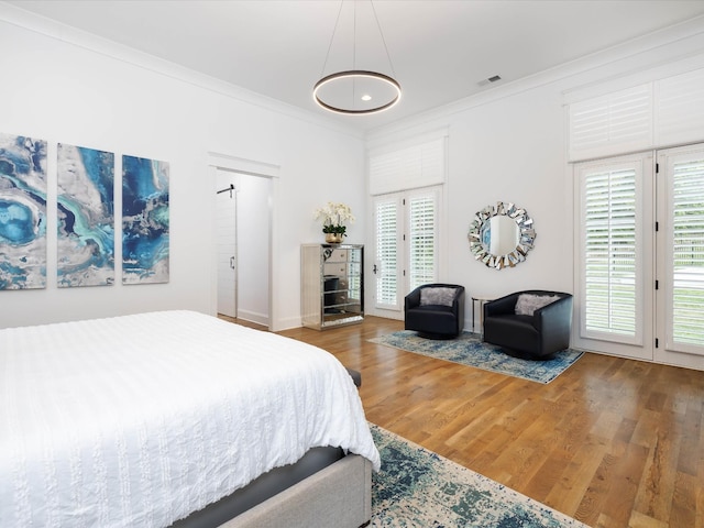 bedroom featuring visible vents, ornamental molding, wood finished floors, access to exterior, and multiple windows