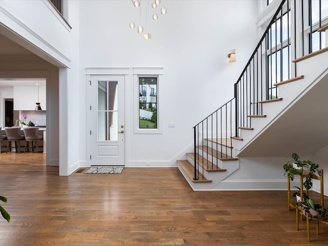 foyer entrance with stairway, a high ceiling, baseboards, and dark wood-type flooring