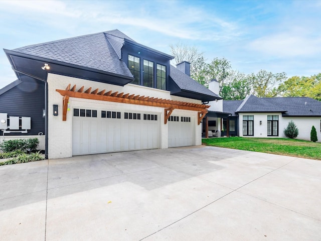 view of front facade featuring an attached garage, a shingled roof, a front lawn, and concrete driveway