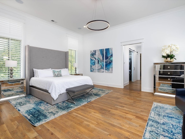 bedroom featuring visible vents, crown molding, baseboards, and wood finished floors