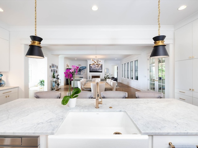 kitchen with open floor plan, white cabinets, and light stone countertops