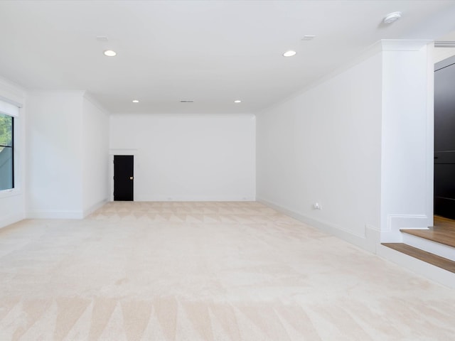 empty room with light colored carpet, crown molding, and baseboards