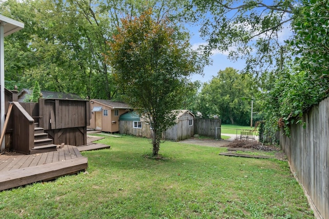 view of yard featuring an outbuilding, a storage unit, a fenced backyard, and a deck