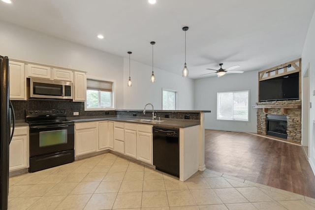 kitchen featuring a peninsula, a sink, open floor plan, black appliances, and dark countertops