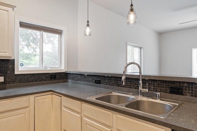 kitchen with dark countertops, hanging light fixtures, backsplash, and a sink