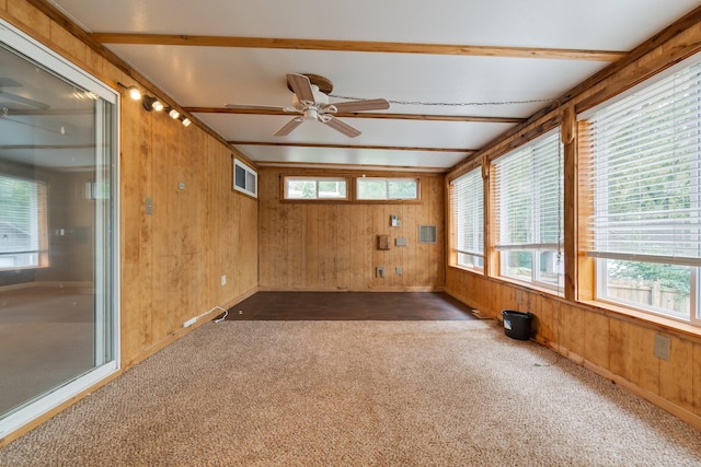 spare room with dark colored carpet, beam ceiling, ceiling fan, and wooden walls