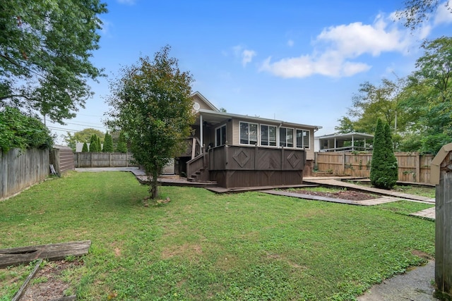 view of yard with a garden, a sunroom, and a fenced backyard