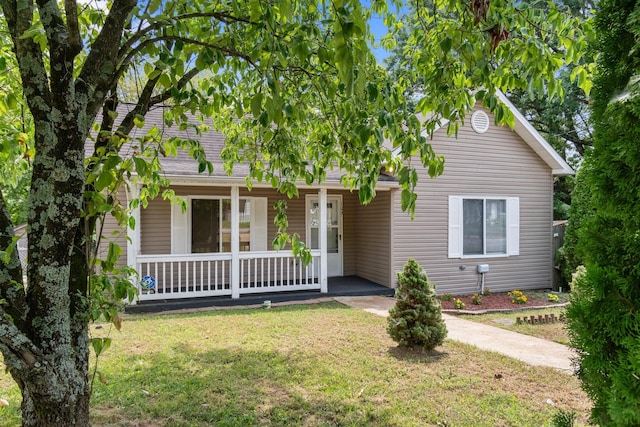 view of property hidden behind natural elements with covered porch and a front yard