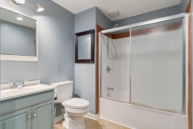 bathroom with bath / shower combo with glass door, toilet, vanity, baseboards, and tile patterned floors