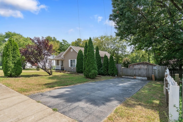 view of front facade featuring fence, driveway, and a front lawn