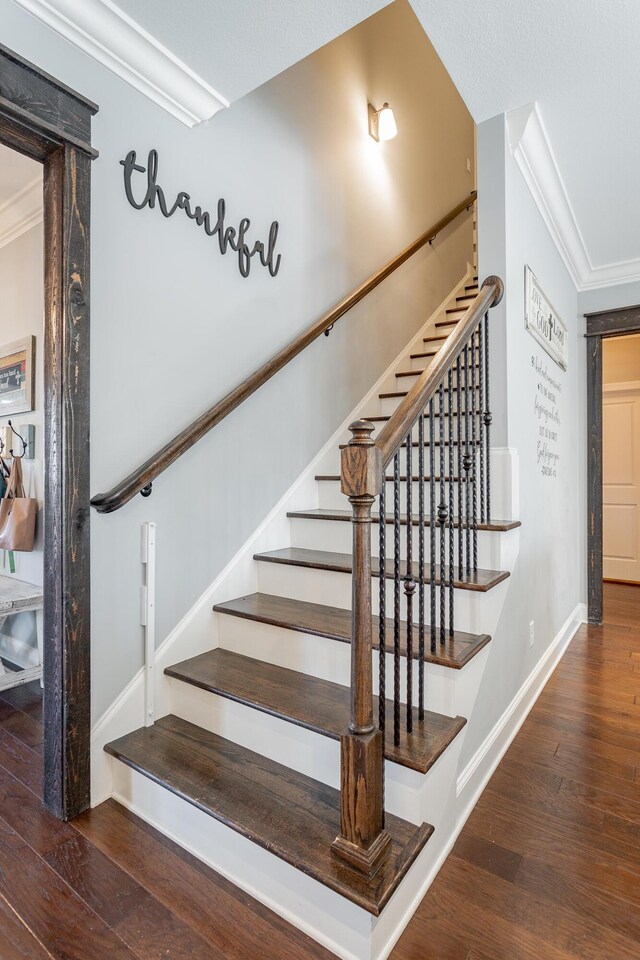 stairs featuring baseboards, wood finished floors, and crown molding