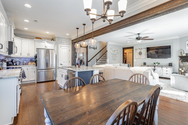 dining space with dark wood finished floors, ornamental molding, stairs, ceiling fan with notable chandelier, and recessed lighting