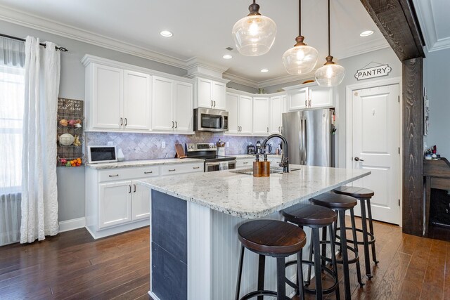 kitchen with white cabinets, pendant lighting, stainless steel appliances, and a sink