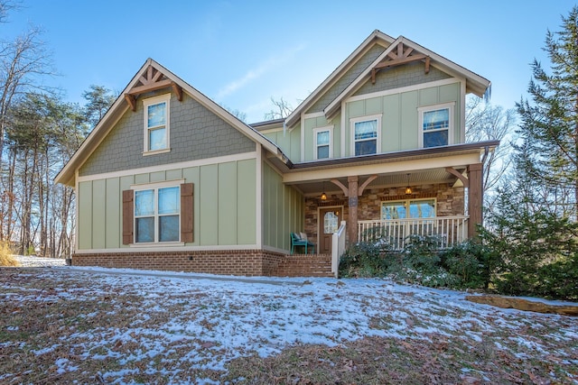 view of front facade featuring board and batten siding, stone siding, and a porch