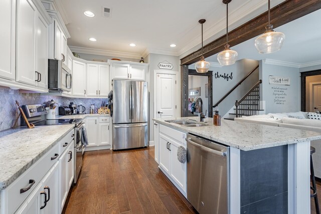 kitchen with hanging light fixtures, white cabinetry, a kitchen island with sink, and appliances with stainless steel finishes