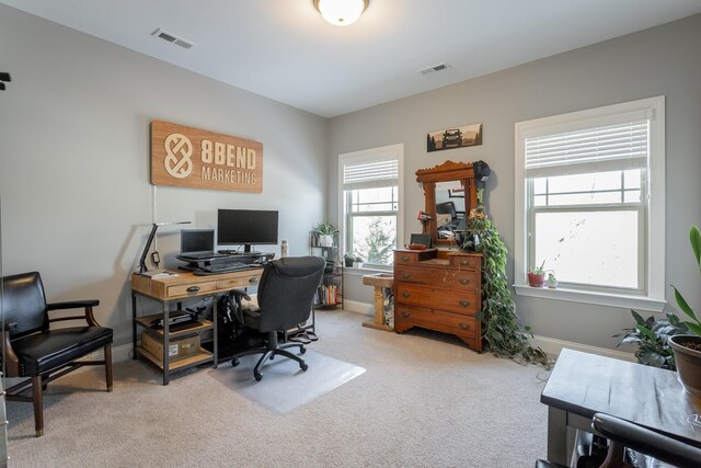 office area featuring baseboards, visible vents, and light colored carpet