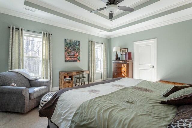 bedroom featuring a tray ceiling, visible vents, crown molding, and carpet