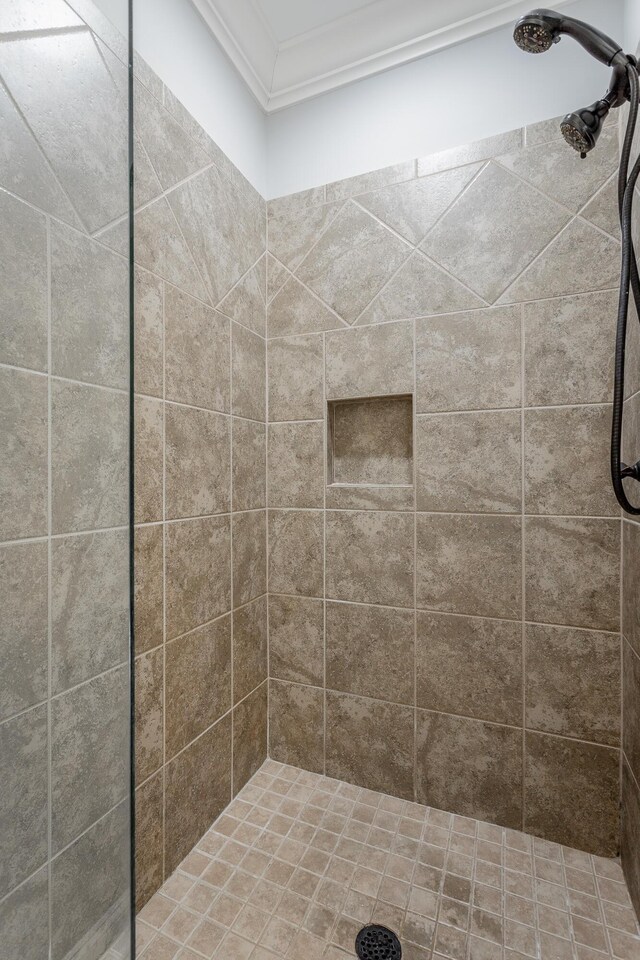 full bath featuring a tile shower and crown molding