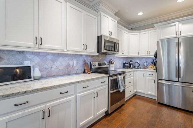 kitchen with light stone counters, white cabinetry, stainless steel appliances, and crown molding