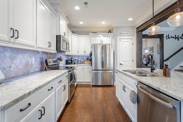 kitchen featuring light stone counters, stainless steel appliances, white cabinetry, pendant lighting, and a sink