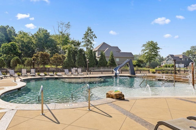 community pool featuring a patio, a water slide, and fence