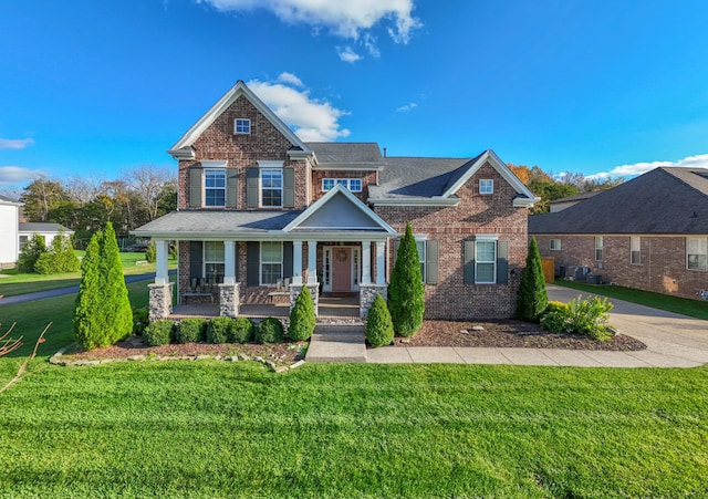 craftsman house with a front yard, covered porch, and brick siding