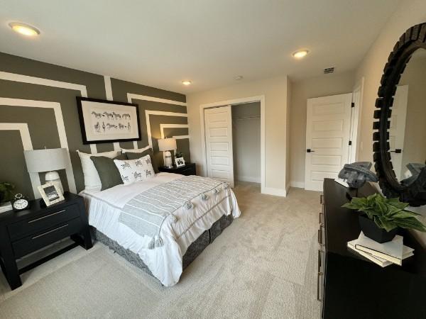 bedroom with recessed lighting, light colored carpet, visible vents, baseboards, and a closet