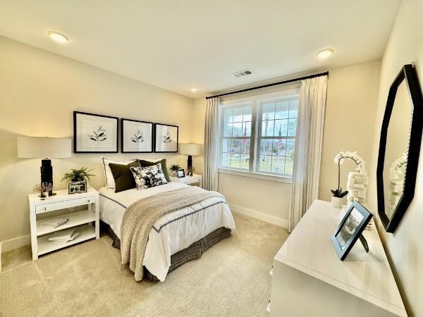 bedroom with visible vents, light carpet, and baseboards