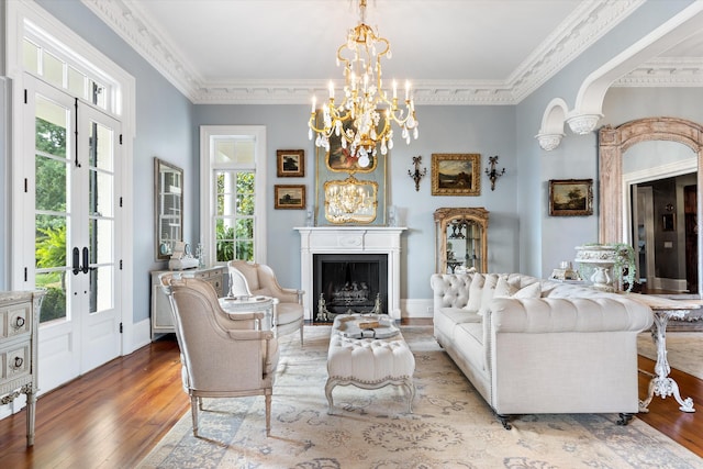 living area featuring ornamental molding, a fireplace, baseboards, and wood finished floors