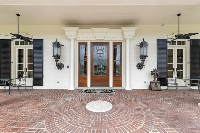 doorway to property featuring a ceiling fan and brick siding