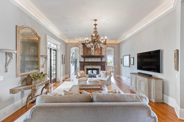 living area with a brick fireplace, plenty of natural light, arched walkways, and ornamental molding